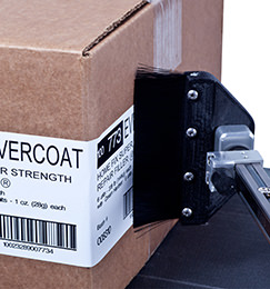 A box is being labelled with an automated label applicator